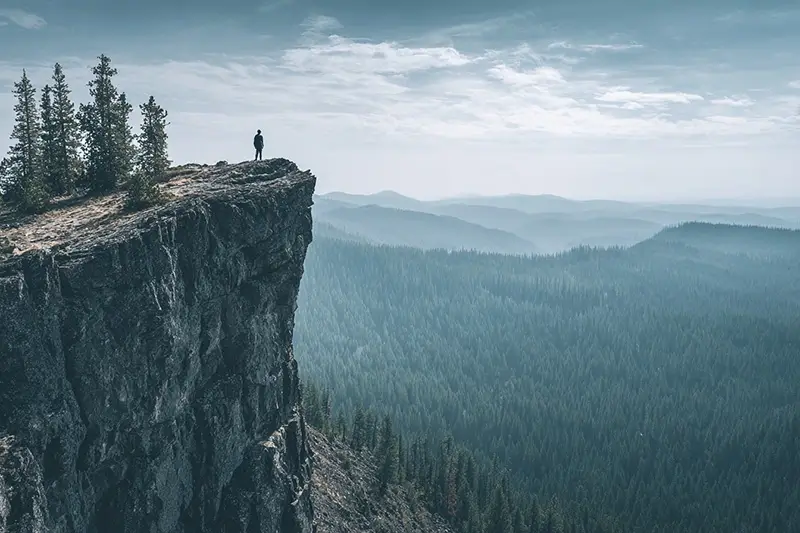 top panoramic view of a person standing at the edge of a cliff stepping back slightly