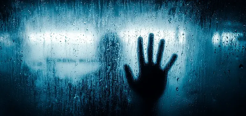 A hand pressed against fogged glass